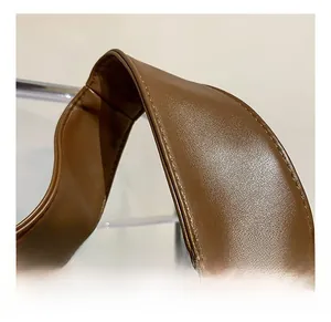 Detail of wide brown leather shoulder strap with visible lychee grain texture and stitching