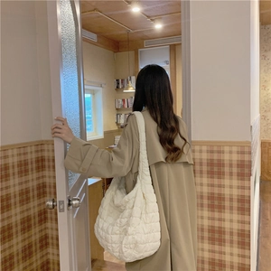 Lifestyle view of white quilted cloud shoulder bag on model wearing a beige trench coat