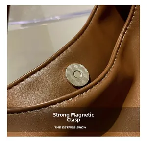 Macro shot of silver magnetic snap closure and pebble grain leather on brown tote bag