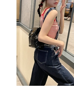 Gros plan du sac à dos en cuir verni noir avec chaînes argentées et fermoir métallique