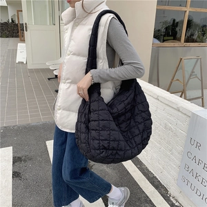 Close-up of a black quilted cloud bag shown on a model during a casual street shoot