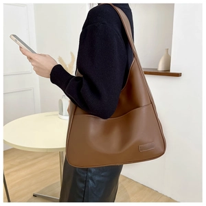 Close-up of brown PU leather tote bag shoulder strap and minimalist curved design detail