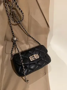 Detail of black quilted leather bag with silver chain and sphere adjustment buckle
