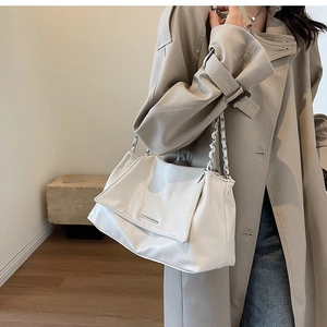Detail of soft cream chain tote bag with pleated texture on model's shoulder