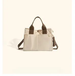 Detail view of beige canvas mommy bag featuring brown handles and spacious side pockets