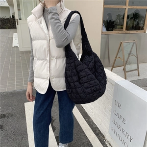 Detail of black quilted cloud bag with pleated texture shown in a street style outfit