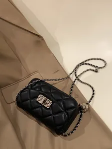 Detailed view of quilted black leather texture and gold metal chain strap on a crossbody bag