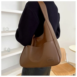 Detail view of large brown soft leather hobo bag with side pocket shown on a model