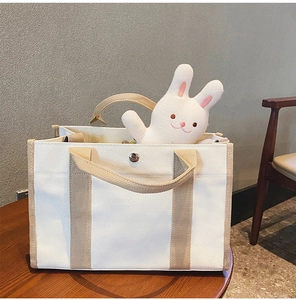 Dettaglio borsa mamma in tela con cinturini marroni e peluche di coniglio all'interno