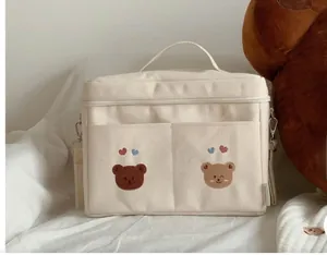 Detail of cute embroidered bear pattern on beige canvas stroller bag with top handle