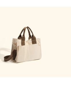 Detail of multi-pocket canvas tote bag showing stitching and side storage pockets