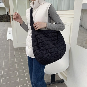 Detailed view of black quilted crossbody bag with soft cloud shape and wide shoulder strap
