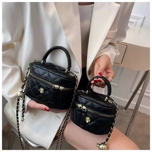 Detail of two black quilted leather mini bags with gold camellia and chain strap