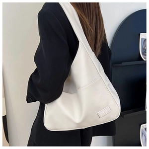 Detailed close-up of a white leather tote bag featuring a front pocket and stylish patch