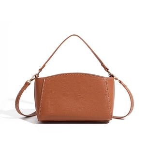 Detail of brown litchi grain leather bag with contrast stitching and gold-tone hardware