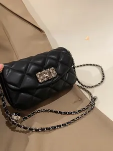 Close-up of black quilted leather texture and gold chain strap on flap crossbody bag
