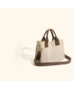Detail of canvas tote bag showing side storage pockets and durable brown strap attachments