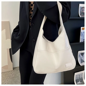 Detailed view of cream white soft leather hobo bag worn with a black blazer jacket