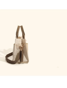 Detail view of the cream canvas diaper bag with brown straps and golden metal hardware