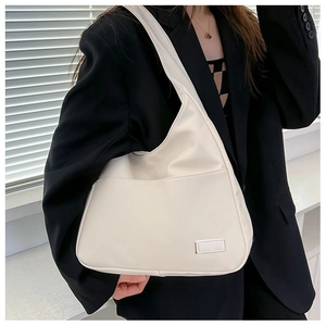 Detail of minimalist cream faux leather hobo bag with front pocket and metal tag