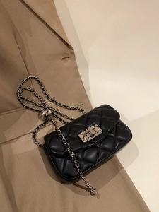 Close-up of black quilted leather crossbody bag with silver chain strap and metal lock