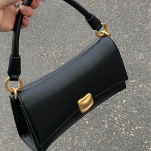 Dettaglio della borsa baguette in pelle nera con un'elegante fibbia in metallo dorato