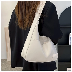 Detail view of large cream hobo bag showing minimalist pocket and smooth leather texture