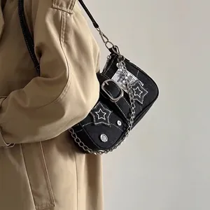 Detail of black denim bag featuring white star patches and heavy silver metal chain