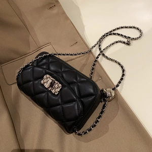 Macro shot of silver sphere buckle on black quilted leather crossbody bag chain