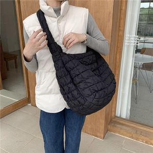 Close-up of black quilted cloud bag with padded texture and wide shoulder strap