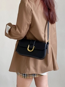 Détail de la boucle dorée en U sur un sac à bandoulière rectangulaire en cuir noir élégant