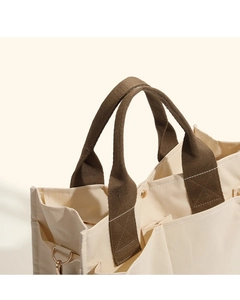 Close-up of cream canvas tote bag with reinforced brown handles and metal D-ring attachment