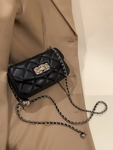 Detailed view of quilted black leather bag with gold metal ball adjustment on chain strap