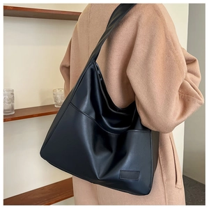 Detail of black faux leather tote bag showing spacious design and textured material