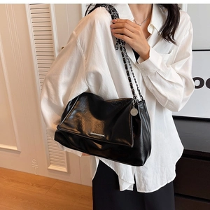 Close-up of black pleated faux leather shoulder bag with silver hardware and chain strap