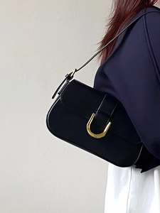 Détail d'un sac sous les bras en cuir noir minimaliste avec boucle dorée décorative en U