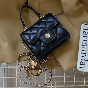 Mini borsa trapuntata nera con chiusura a fiore dorato e tracolla a catena su blazer