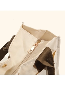Detail of canvas tote bag with metal zipper and durable brown woven handles