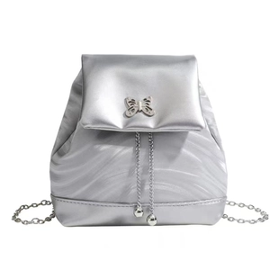 Sac à dos argenté en cuir brillant avec fermoir papillon et bandoulière en chaîne