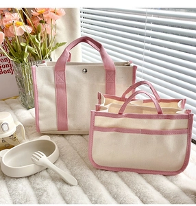 Dettaglio della borsa fasciatoio in tela beige con manici rosa e organizer interno