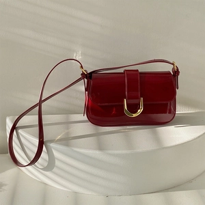 Détail d'un sac à bandoulière en cuir verni rouge foncé brillant avec boucle dorée