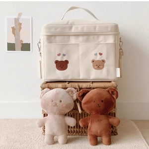 Detail of beige canvas baby organizer bag with cute bear embroidery and plush doll