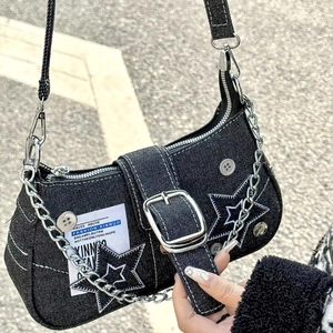 Detail of black denim Y2K shoulder bag with star patches and silver chain accents