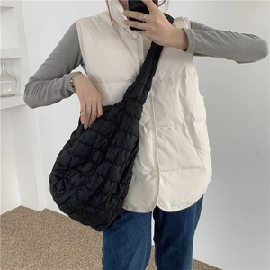 Close-up of black quilted cloud bag with square pattern shown on model in minimal interior