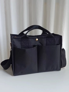 Detail of black canvas utility bag with deep front pockets and adjustable shoulder strap