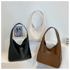 Three large soft leather tote bags in black, beige, and brown on a white step background