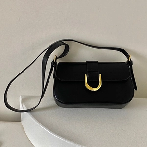 Détail du sac à bandoulière en cuir noir mat avec boucle en fer à cheval dorée