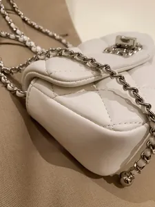 Close-up of premium white quilted leather texture with silver metal chain details