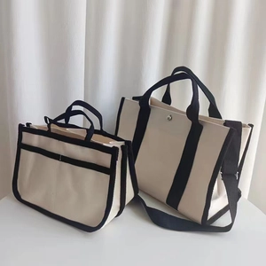 Dettaglio di borse tote in tela bianca con cinturini neri in diverse dimensioni