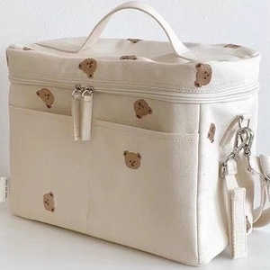 Detailed view of cream canvas diaper bag with brown bear embroidery and sturdy zippers